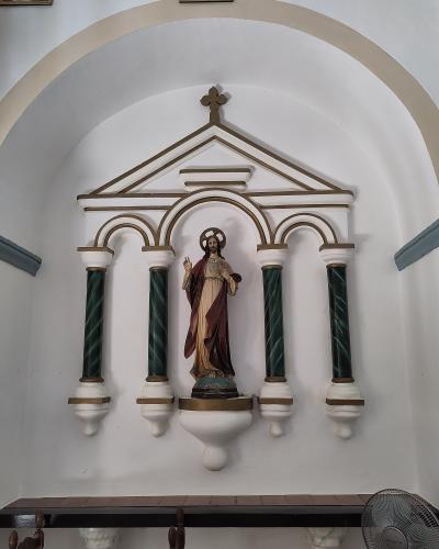 The image shows an interior religious niche containing a statue of Jesus Christ (Sacred Heart) set within a white and gold architectural structure with green marbleized columns, located inside a church.