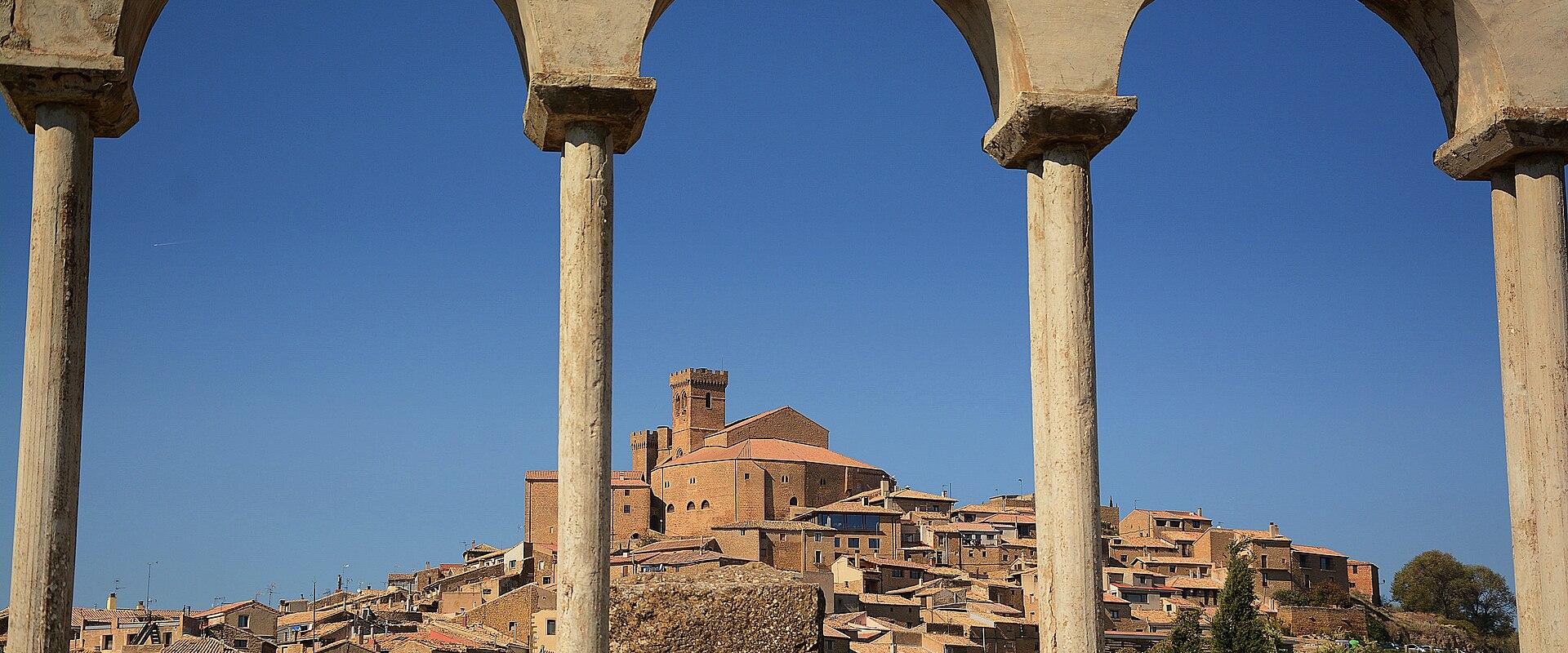 The hilltop village of Ujué seen through a stone arcade