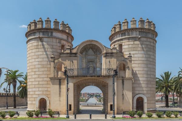 The image shows the Puerta de Palmas, a monumental city gate with two large cylindrical towers and a central archway, located in Badajoz, Spain.