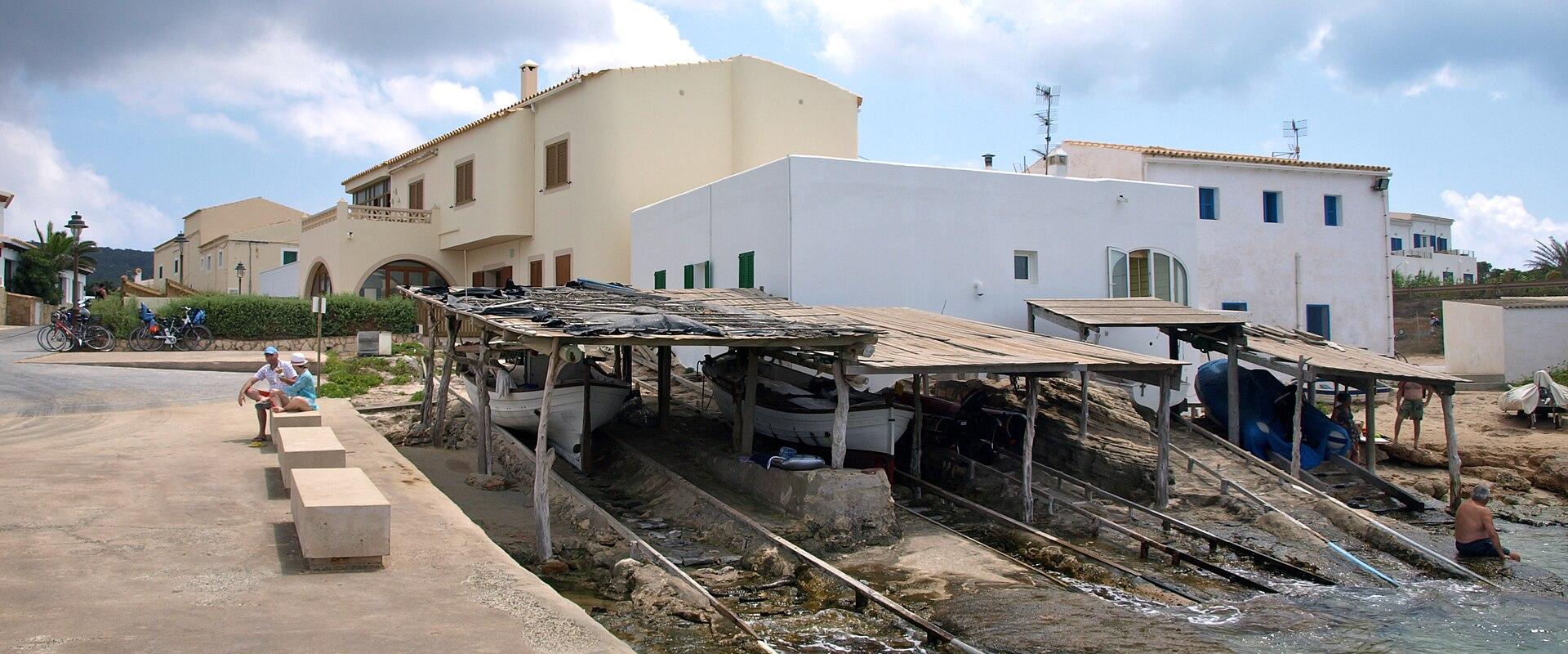 Fishermen's boat sheds along the rocky shore of Es Caló, Formentera