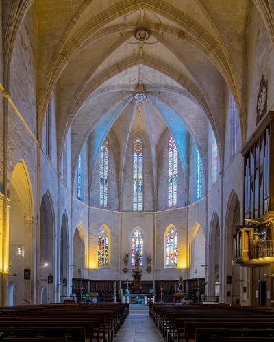 The interior of a large stone church showing the main nave, vaulted ceilings, stained glass windows, and an organ on the right side.
