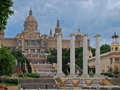 A view from a tiled terrace looking through a colonnade towards the large central dome and facade of the Palau Nacional.