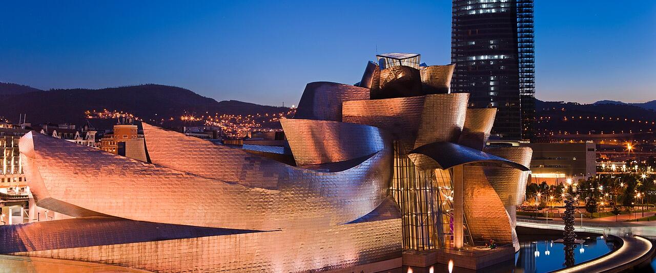 The Guggenheim Museum Bilbao lit at blue hour beside the river Nervión