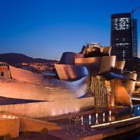 The Guggenheim Museum Bilbao lit at blue hour beside the river Nervión