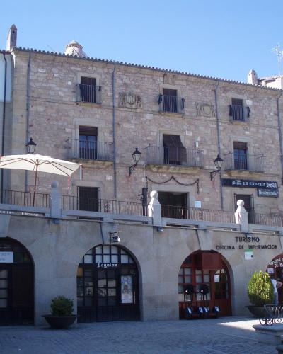 A stone building with arched ground-floor entrances, a terrace with umbrellas, and signage reading "Casa la cadena" and "Turismo Oficina de Información".