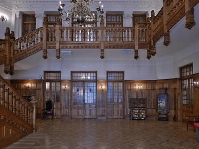 The image shows a grand interior hall with elaborate wooden staircases, a large chandelier, and wood-paneled walls, identified by the filename as the "Recibidor" (Reception Hall) of the Palacio de la Magdalena.