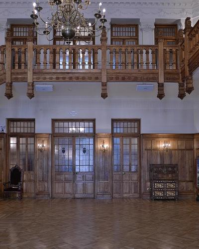 The image shows a grand interior hall with elaborate wooden staircases, a large chandelier, and wood-paneled walls, identified by the filename as the "Recibidor" (Reception Hall) of the Palacio de la Magdalena.