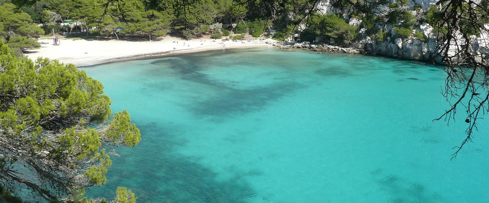 The turquoise cove of Cala Macarella framed by pines, Menorca