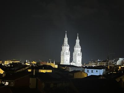 A night photograph showing two illuminated, ornate white bell towers rising above the dark rooftops of a city.