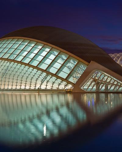 The image shows the L'Hemisfèric (Eye of Science) and the L'Oceanogràfic buildings within the City of Arts and Sciences complex, illuminated at night with reflections in the water.